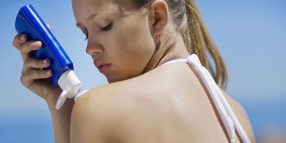 young woman applying sunscreen, close up