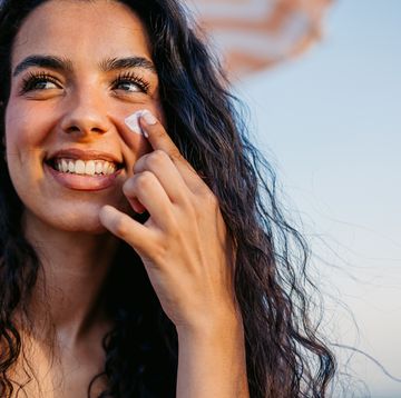 young woman applying sunscreen on her face on the beach in barcelona in spain