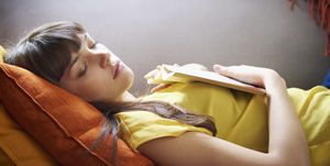 Young woman asleep with book on sofa