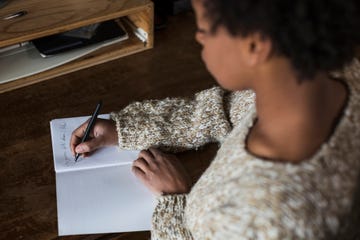 young woman at desk writing in notebook