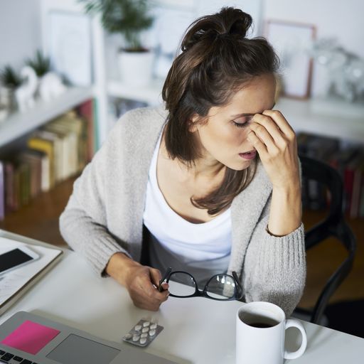 Young woman at home at desk suffering headache
