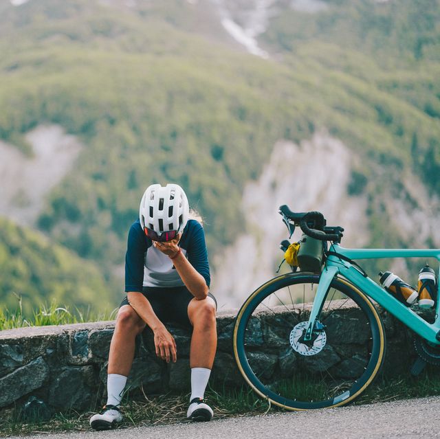 young woman bicyclist pause on road in mountains