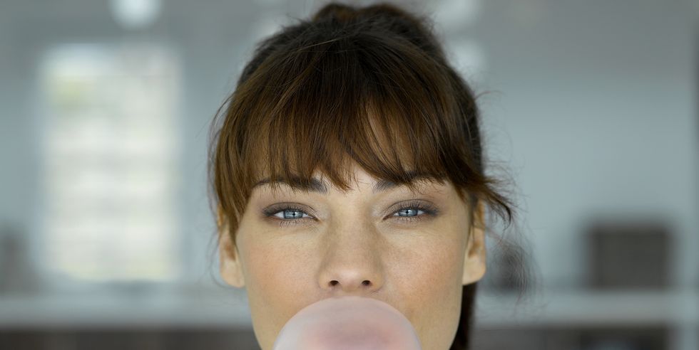 young woman blowing bubble, indoors, portrait