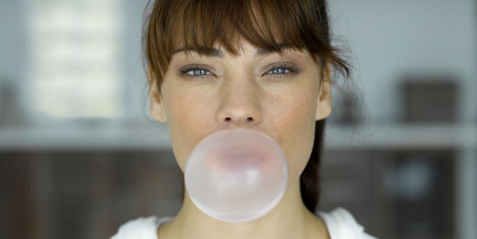young woman blowing bubble, indoors, portrait