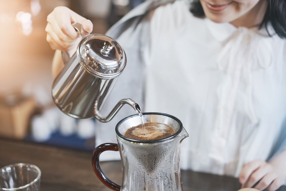 a young woman brewing coffee