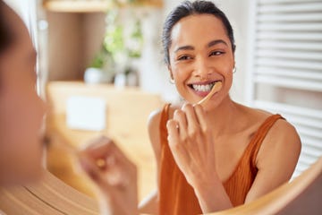 young woman brushing teeth at home with toothbrush