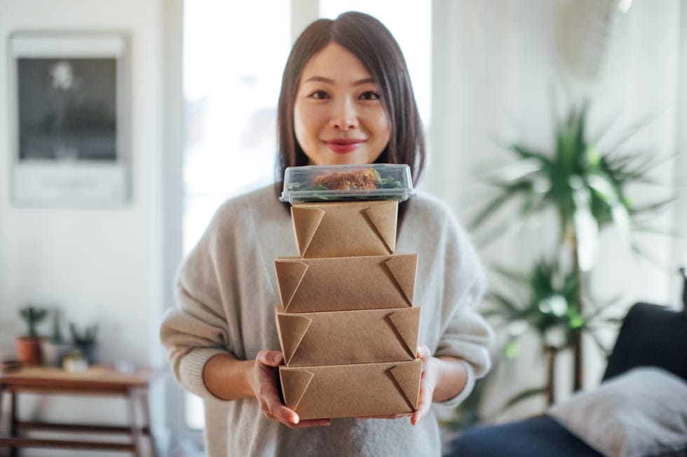 young woman carrying takeaway food boxes