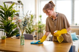 young woman cleaning the dining table surface