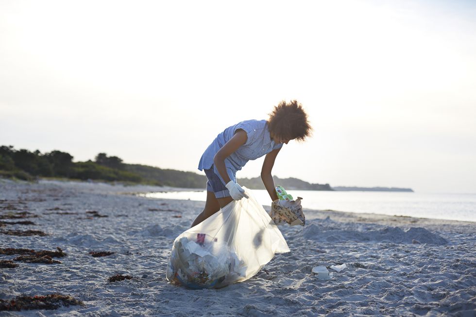 young woman collecting trash on beach