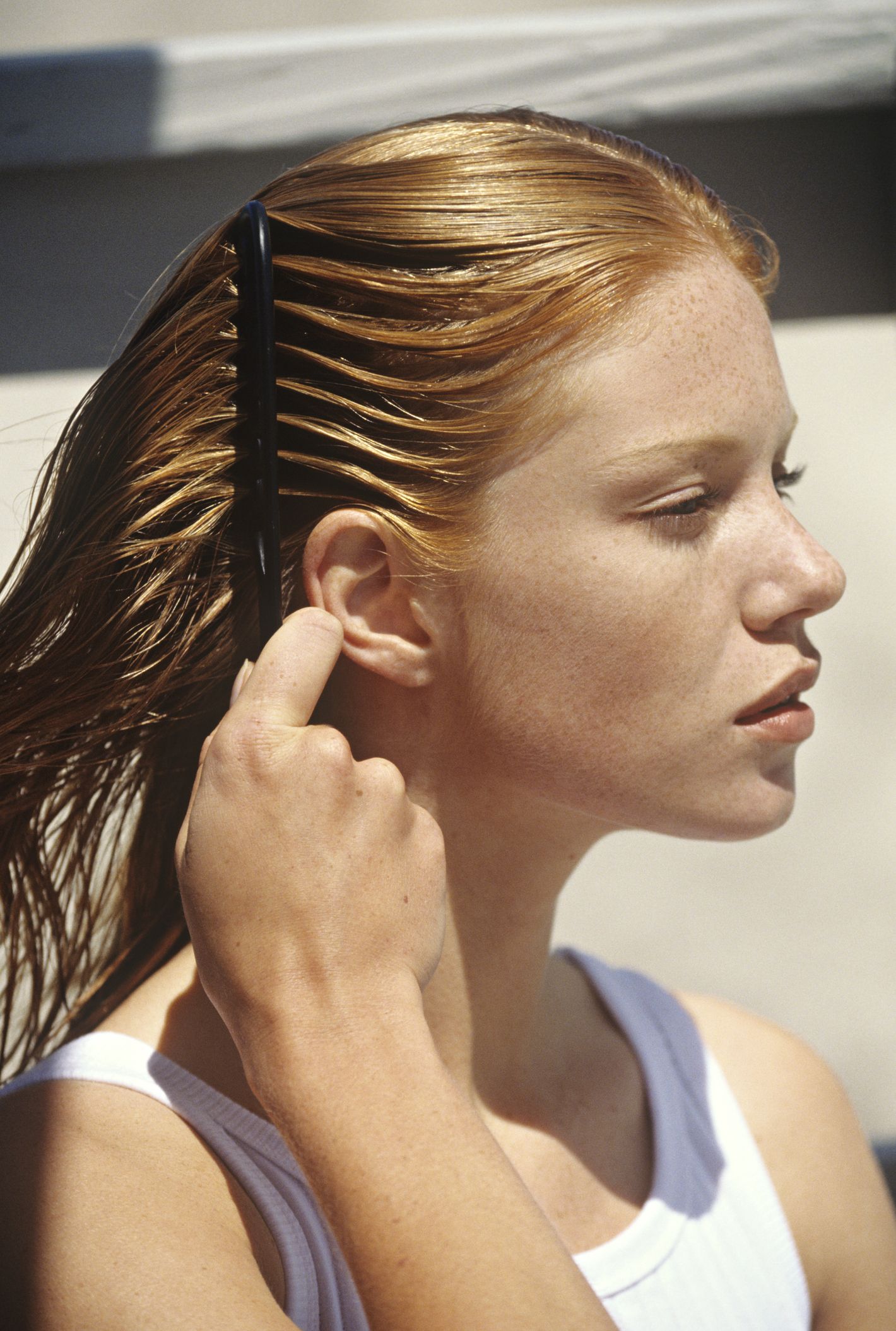 young woman combing her hair, outdoors