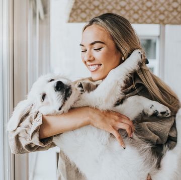 young woman cuddles her 12 week old golden retriever puppy