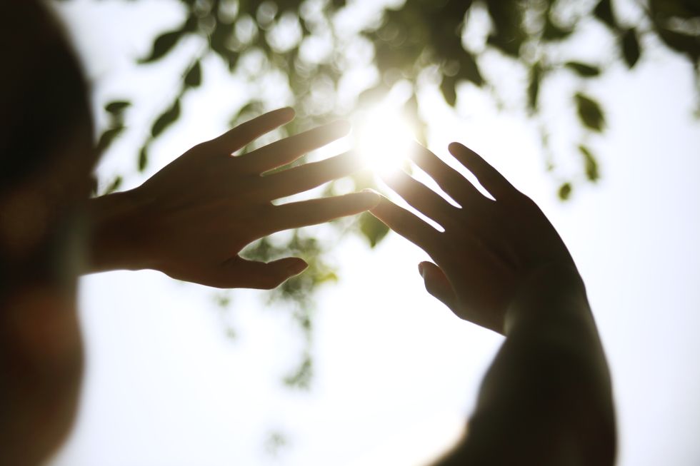 young woman cupping hands around sun