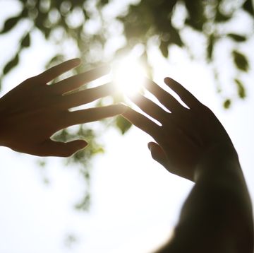 young woman cupping hands around sun