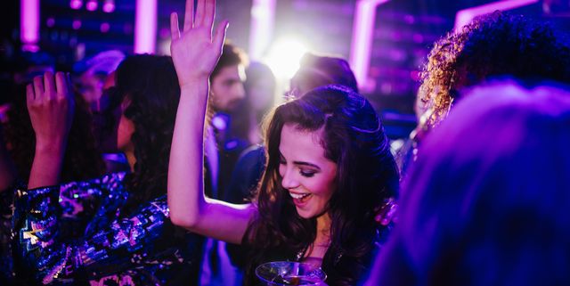 Young woman dancing in a club with a cocktail