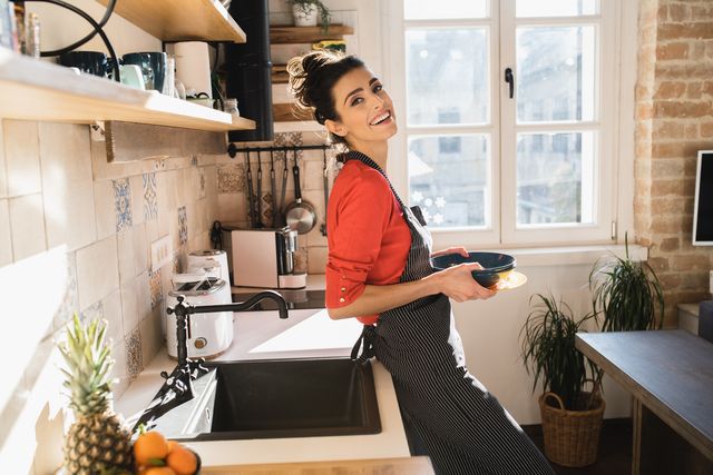 young woman doing dishes at her kitchen