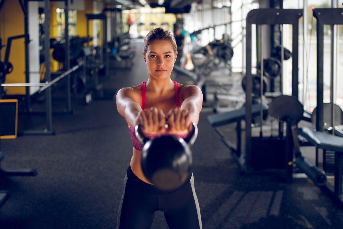 Young woman doing kettlebell exercise at gym
