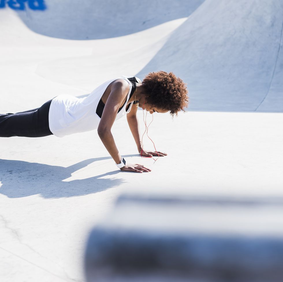 young woman doing pushups in skatepark