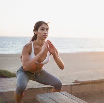 Young woman doing squat jumps on beach Young woman doing squat jumps on beach