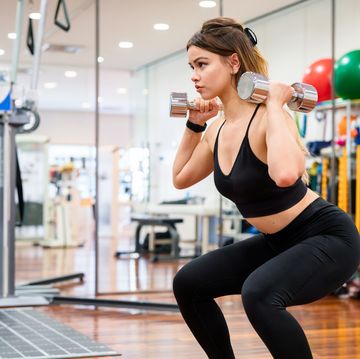 young woman doing squats whilst holding weights