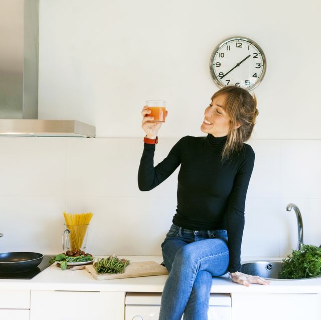 young woman drinking fresh grapefruit juice in her kitchen