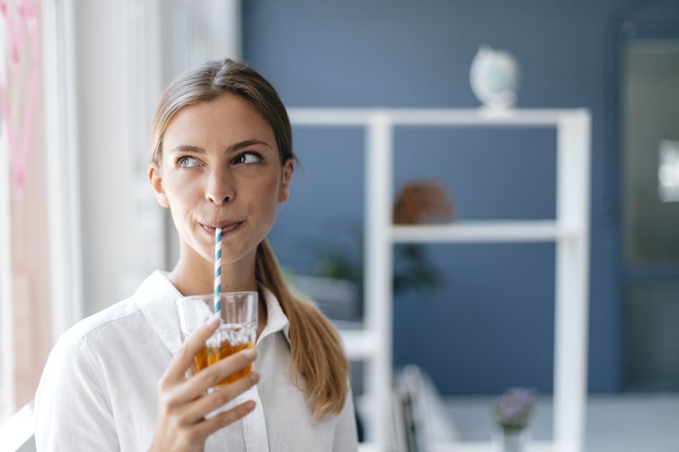 mujer joven tomando una bebida en un vaso con pajita