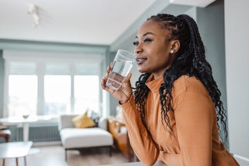 young woman drinking water at home