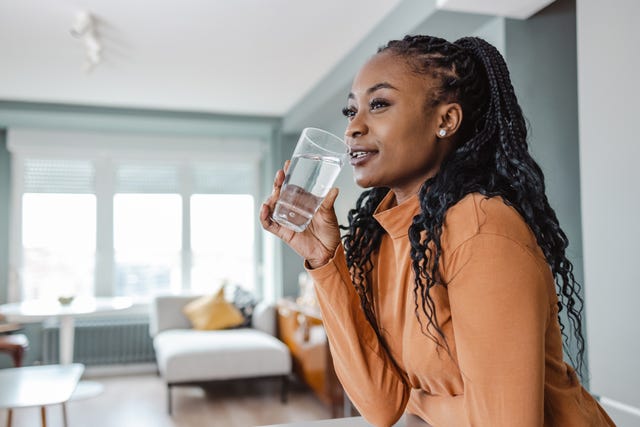 young woman drinking water at home