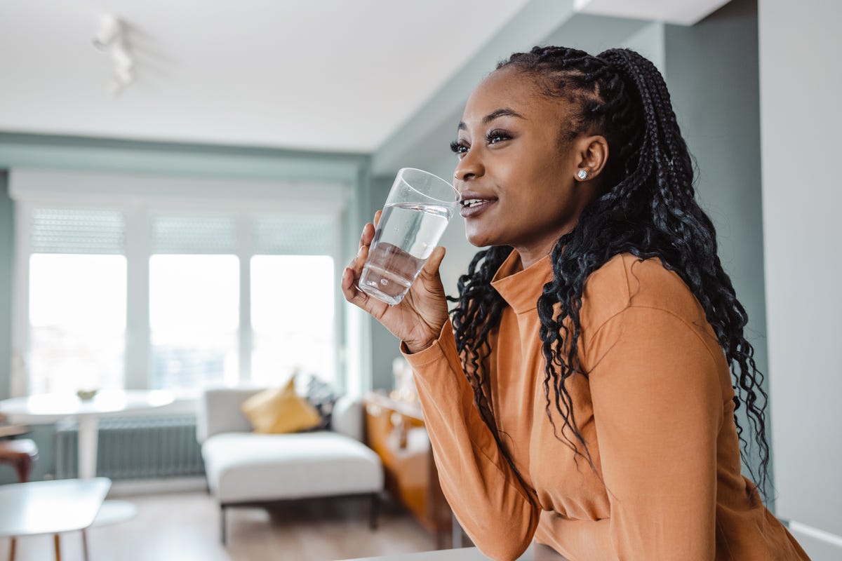 young woman drinking water at home