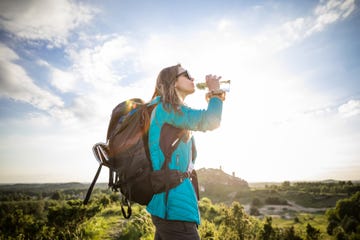 young woman drinking water at sunset