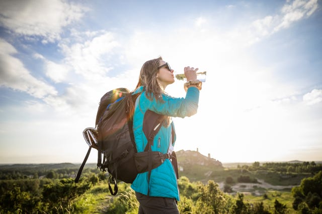 young woman drinking water at sunset
