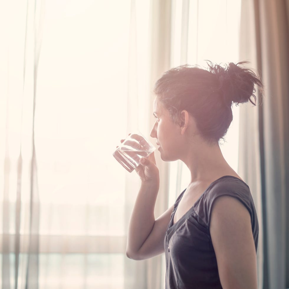 young woman drinking water in the bedroom