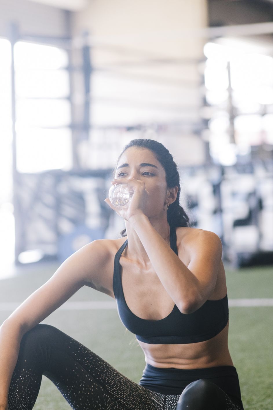 young woman drinks water at gym