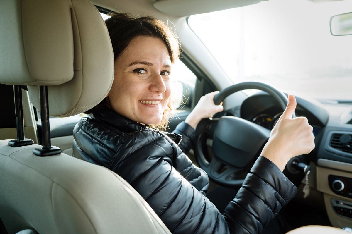 young woman driver with thumbs up in a car