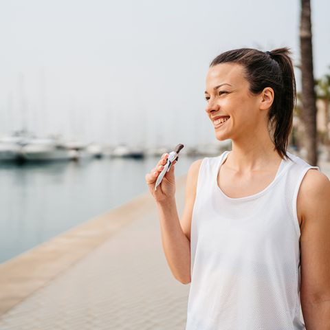 young woman eating a protein bar after training on the quayside in palma de mallorca in spain