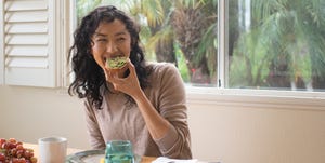 jonge vrouw eet een broodje met avocado thuis