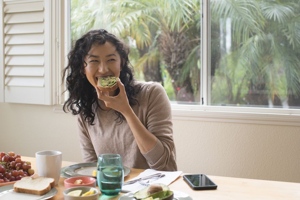 young woman eating avocado toast at home