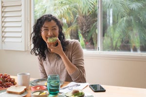 jonge vrouw zit aan tafel, eet brood met avocado