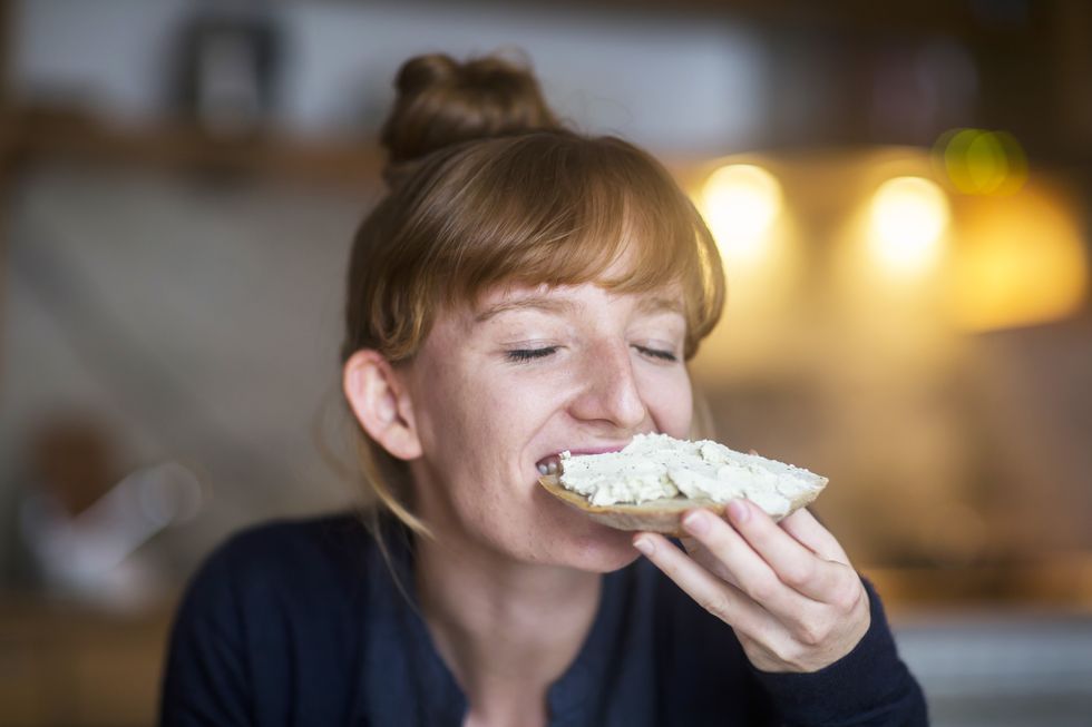 young woman eating bread with cream cheese
