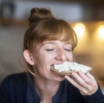 young woman eating bread with cream cheese
