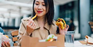 young woman eating burger and chips outdoors
