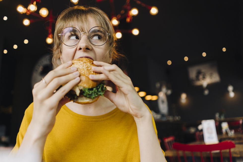 young woman eating burger in a restaurant