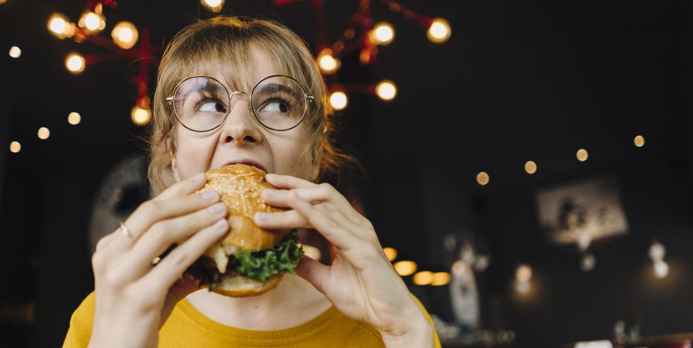 young woman eating burger in a restaurant