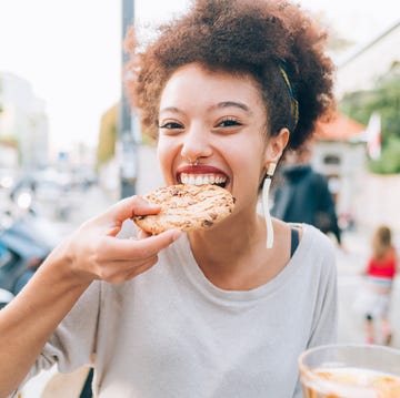 young woman eating cookie at outdoor cafe