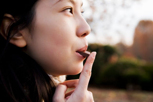 young woman eating piece of chocolate