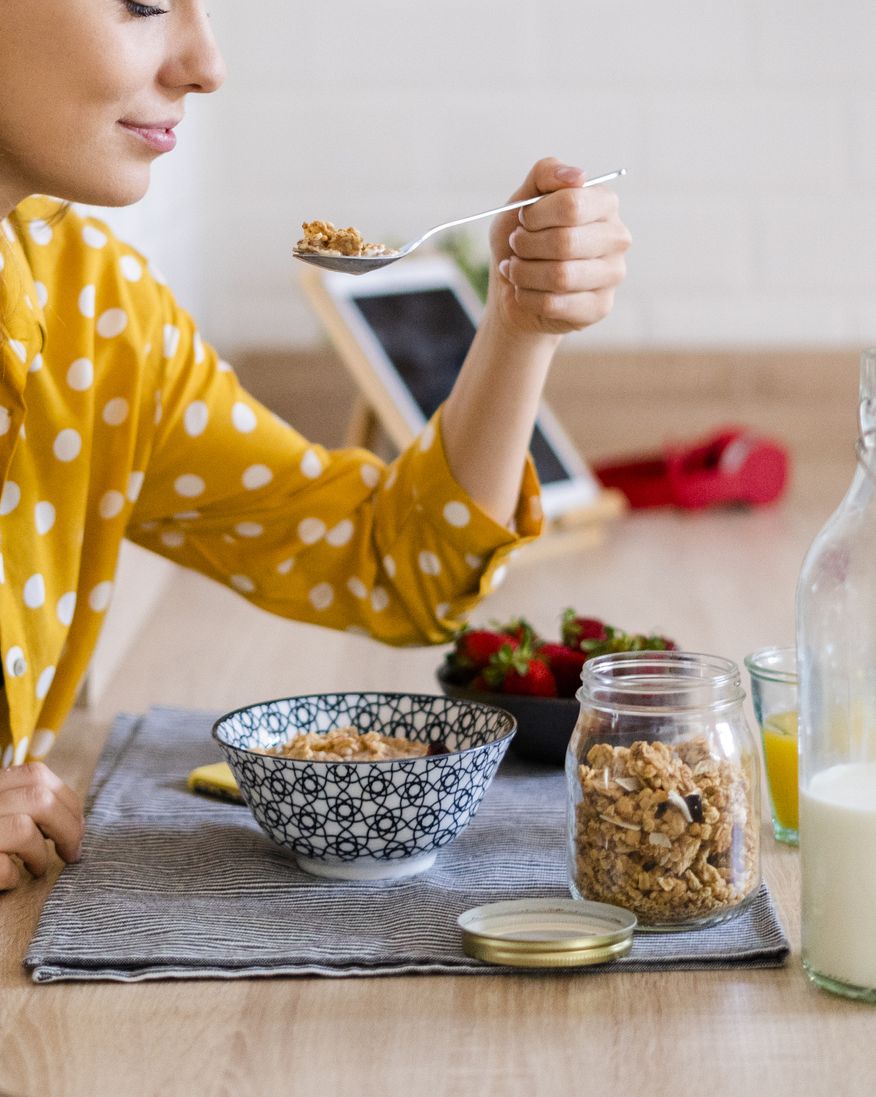 young woman enjoying breakfast in kitchen at home
