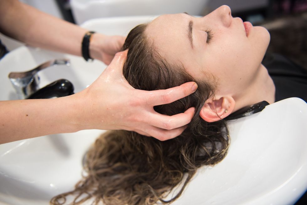 young woman enjoying head massage while washing her hair in a hair salon