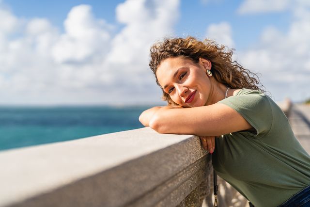 mujer jover pelo rizado mirando al mar