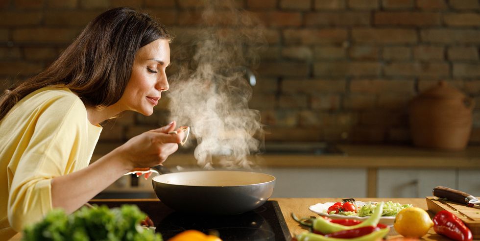 young woman enjoying while cooking meal in the kitchen