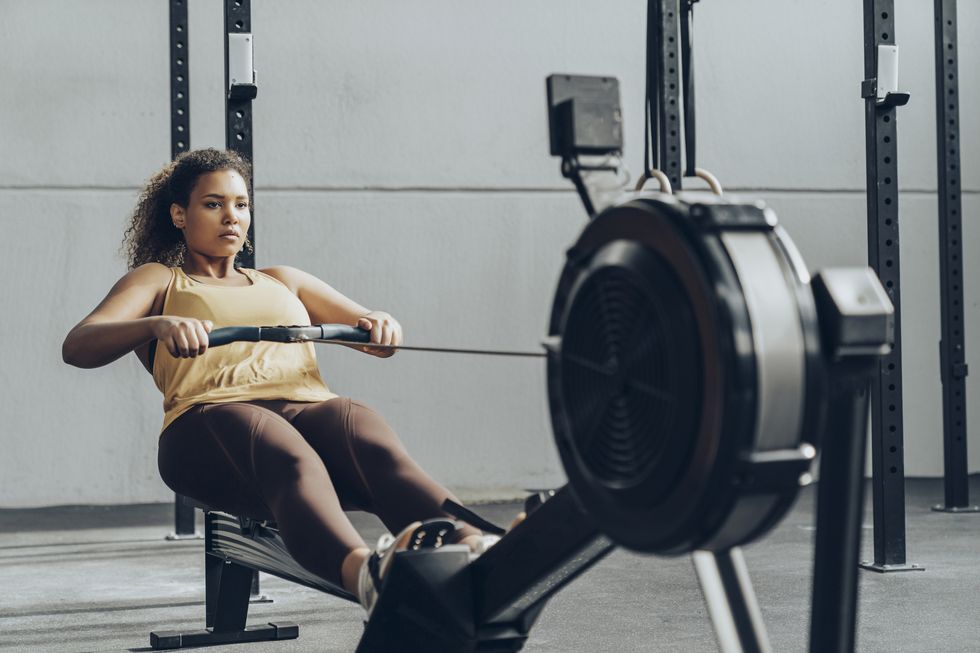 young woman exercising in gym with rowing machine
