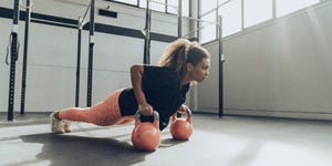 young woman exercising with kettlebells in gym